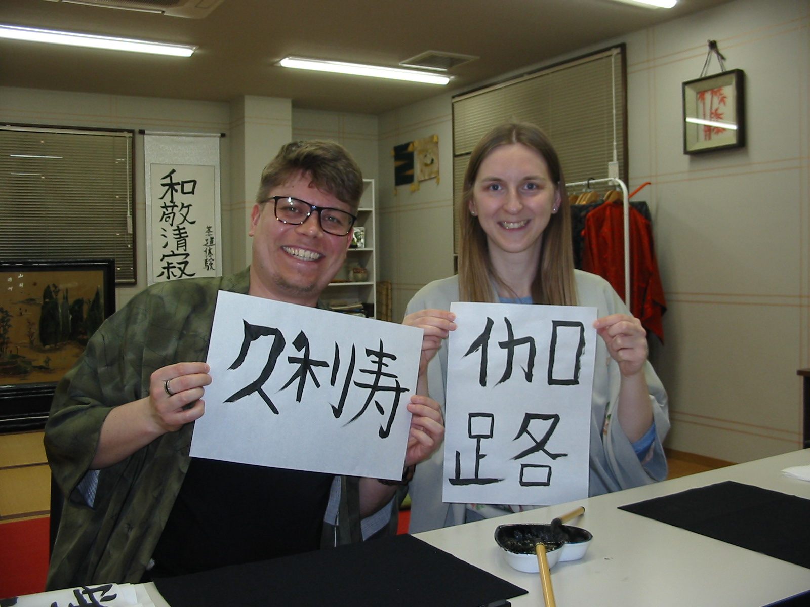 Two guests proudly holding up their calligraphy